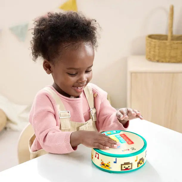 Child playing with a colorful toy in a room with a wooden cabinet and decorative items.